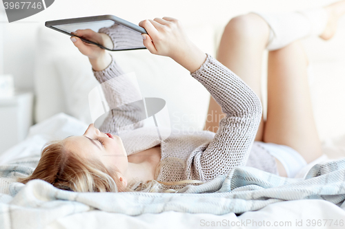 Image of happy young woman with tablet pc in bed at home