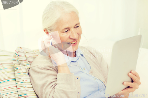 Image of senior woman with tablet pc and earphones at home