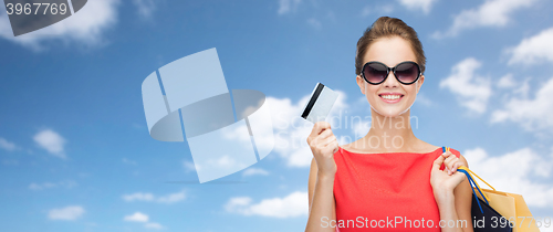 Image of woman with shopping bags and credit card over sky