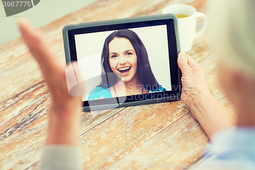 Image of senior woman with photo on tablet pc at home