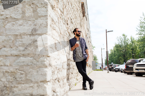 Image of man with smartphone at stone wall on city street