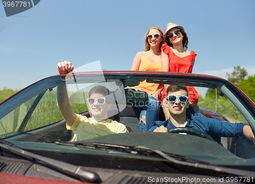 Image of happy friends driving in cabriolet car at country