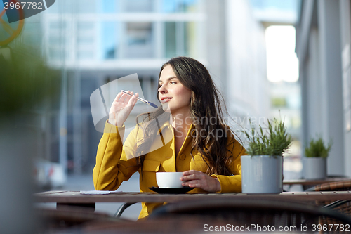 Image of happy woman with notebook drinking cocoa at cafe
