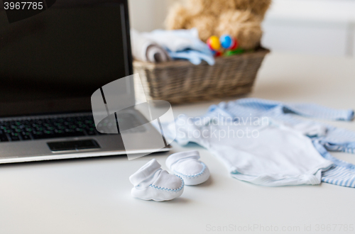 Image of close up of baby clothes, toys and laptop at home