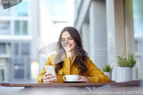 Image of happy woman texting on smartphone at city cafe