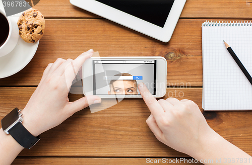 Image of close up of woman with smartphone on wooden table