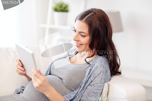 Image of happy pregnant woman with tablet pc at home