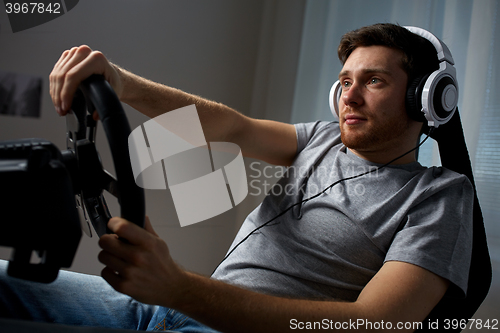 Image of man playing car racing video game at home