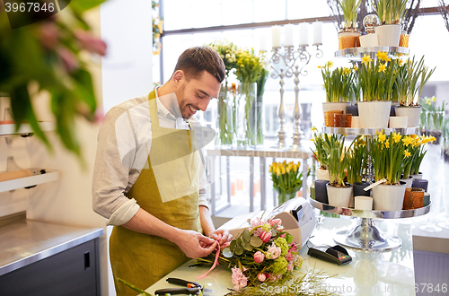 Image of smiling florist man making bunch at flower shop