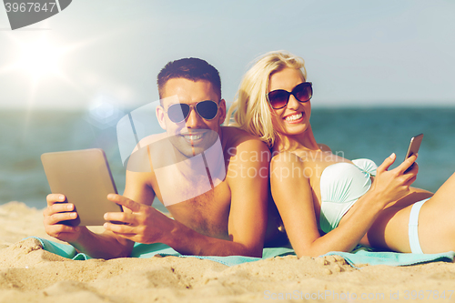 Image of happy couple with tablet pc sunbathing on beach