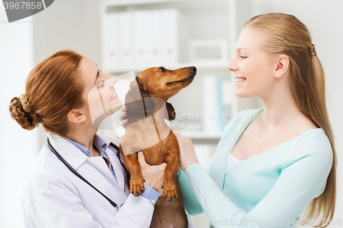 Image of happy woman with dog and doctor at vet clinic