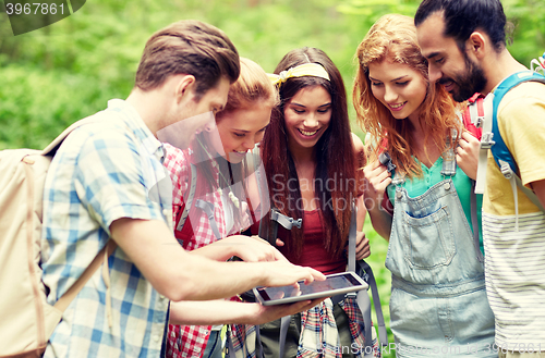 Image of happy friends with backpacks and tablet pc hiking