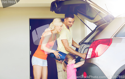 Image of happy family packing things to car at home parking