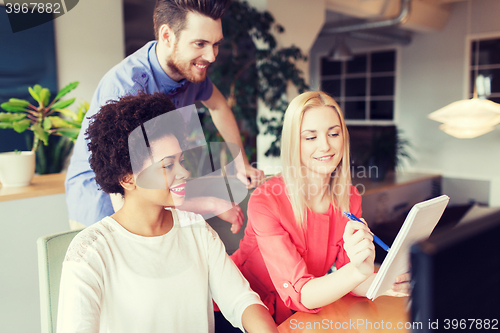 Image of happy creative team with computer in office