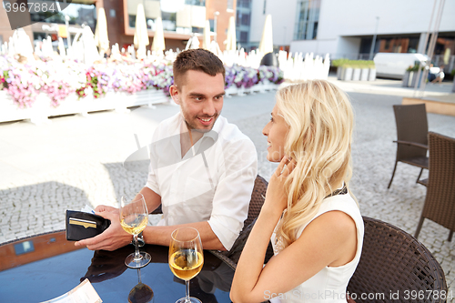 Image of happy couple with wallet paying bill at restaurant