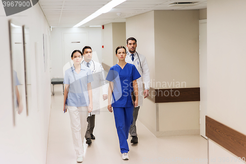 Image of group of medics or doctors walking along hospital