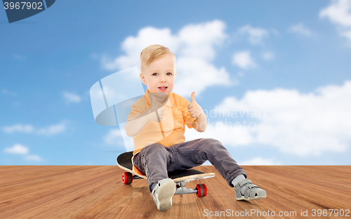 Image of happy little boy on skateboard showing thumbs up