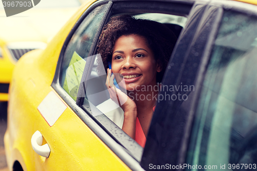 Image of happy african woman calling on smartphone in taxi