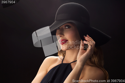 Image of beautiful woman in black hat over dark background