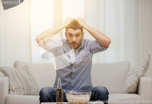 Image of sad man watching sports at home