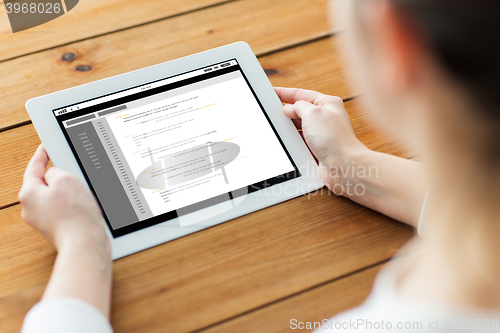 Image of close up of woman with tablet pc on wooden table