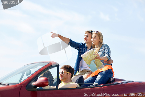 Image of happy friends driving in cabriolet car