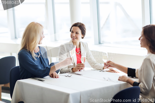 Image of happy women drinking champagne at restaurant