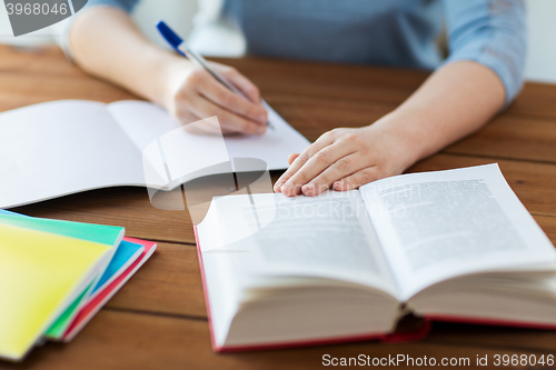 Image of close up of student with book and notebook at home