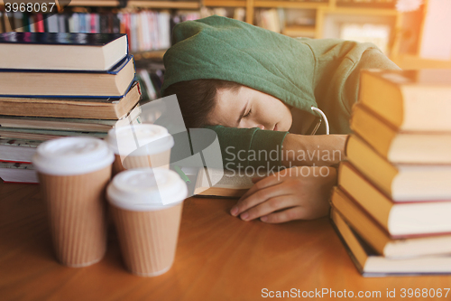 Image of tired student or man with books in library