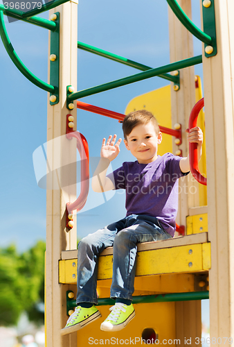 Image of happy little boy climbing on children playground