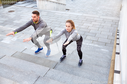 Image of couple doing squats on city street stairs