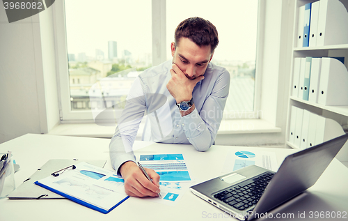 Image of stressed businessman with papers in office