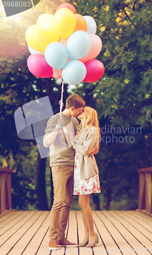 Image of couple with colorful balloons kissing in the park