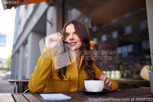 Image of happy woman with notebook drinking cocoa at cafe