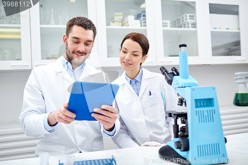 Image of scientists with tablet pc and microscope in lab