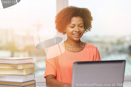 Image of happy african american woman with laptop at home