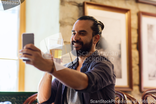 Image of man with smartphone drinking beer at bar or pub