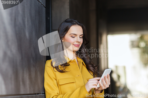 Image of smiling young woman or girl texting on smartphone