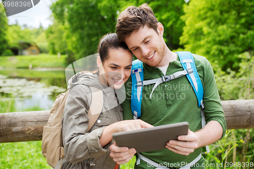 Image of happy couple with backpacks and tablet pc outdoors