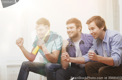 Image of happy male friends with vuvuzela watching sports