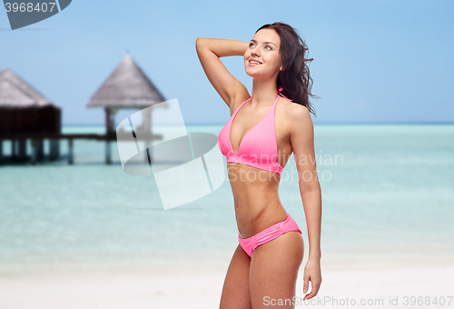 Image of happy young woman in pink bikini swimsuit on beach