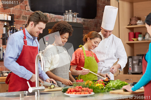 Image of happy friends and chef cook cooking in kitchen