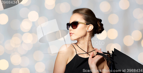 Image of happy woman in black sunglasses with shopping bags