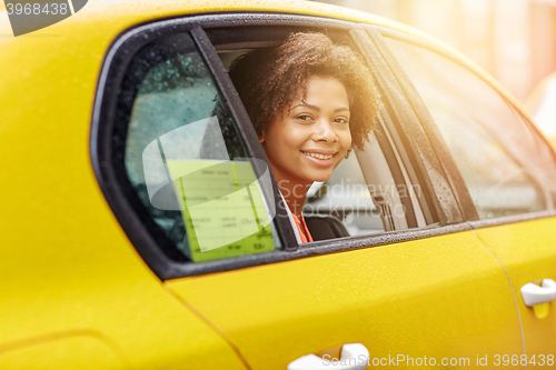 Image of happy african american woman driving in taxi