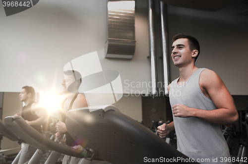 Image of smiling men exercising on treadmill in gym
