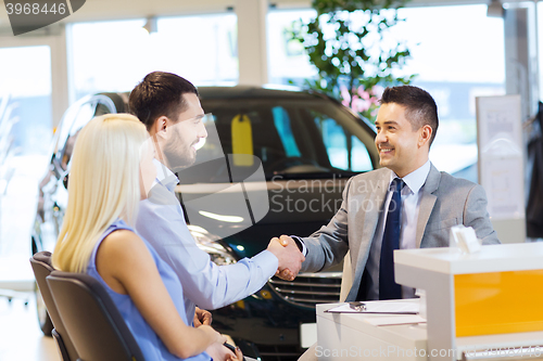 Image of happy couple with car dealer in auto show or salon