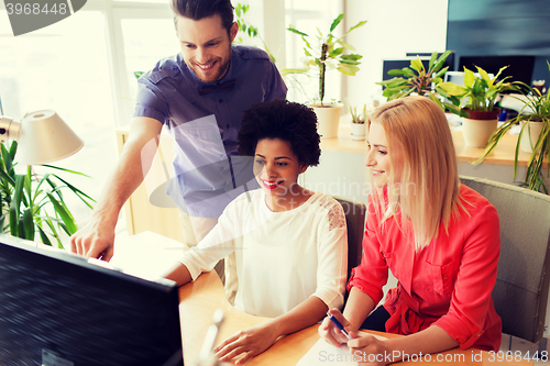 Image of happy creative team with computer in office