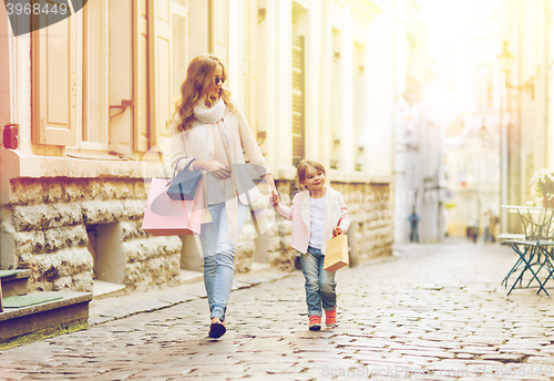 Image of happy mother and child with shopping bags in city