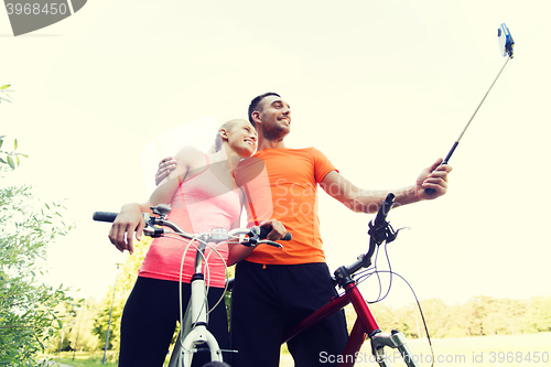 Image of couple with bicycle and smartphone selfie stick