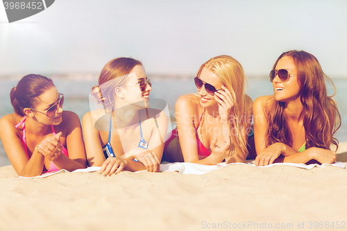 Image of group of smiling women in sunglasses on beach